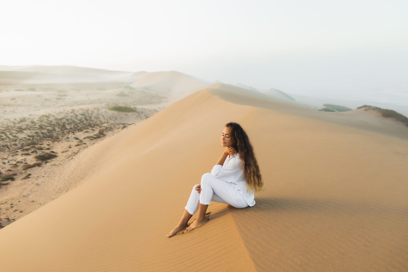 Woman Sitting on dunes of Sahara Desert in Morocco