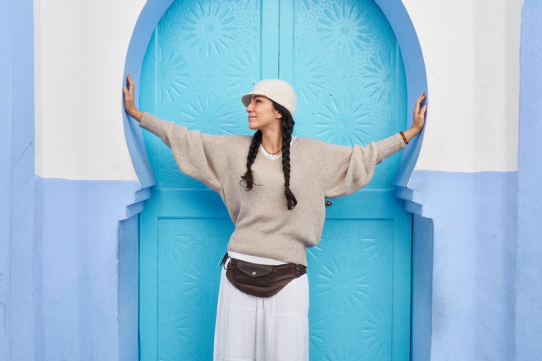 Woman posing in the streets of Chefchaouen wearing comfortable layers for spring weather in Morocco