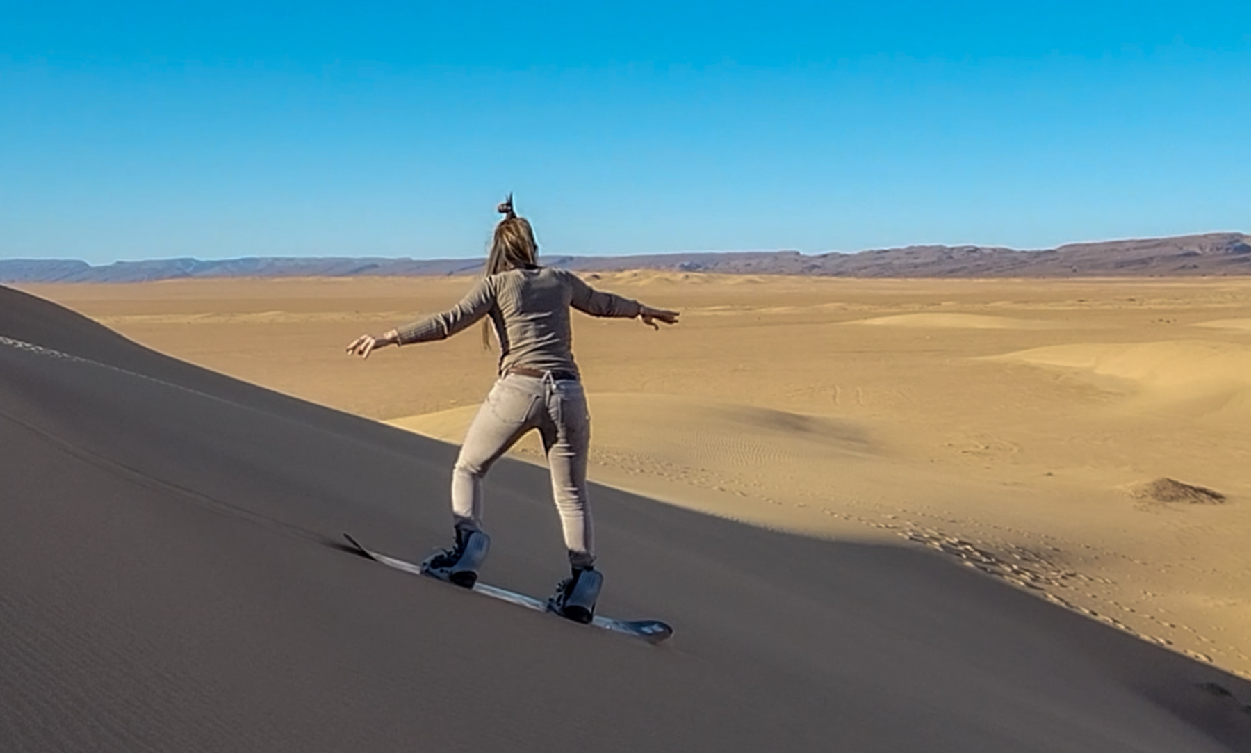 Woman sandboarding in Erg Lihoudi, Sahara Desert, Morocco